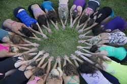 Yoga practitioners in a circle of childs poses with hands reaching inward
