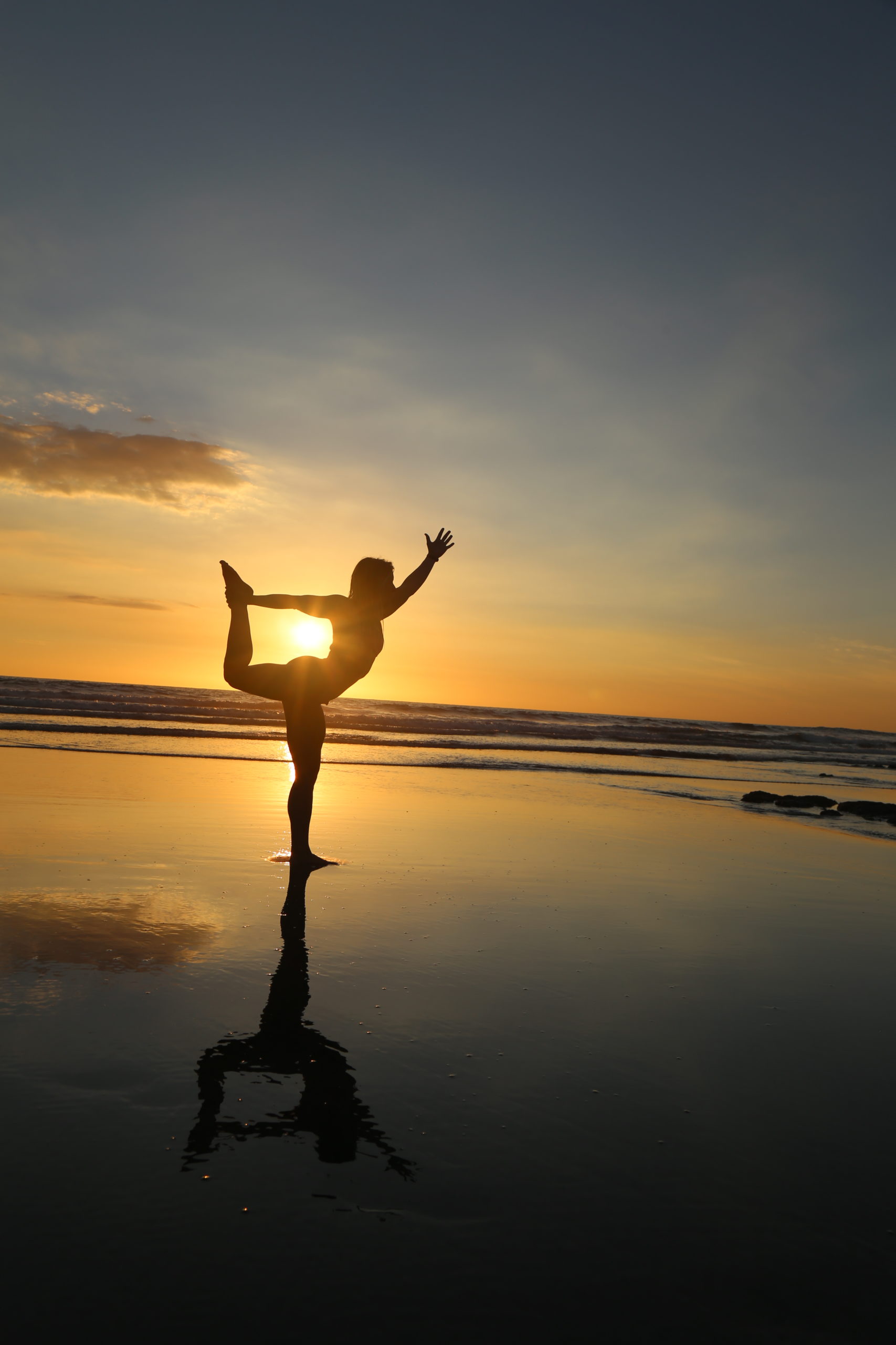 Silhouette of yogi on the beach at sunset in dancer pose