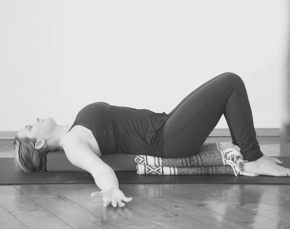 Black and white of Molly Masaoka on yoga mat, blanket and blocks